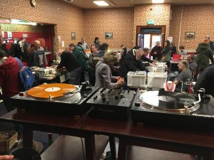 Stalls at a record fair with people milling around and crate-digging