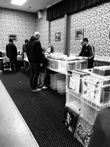 Stalls at a record fair with people milling around and crate-digging
